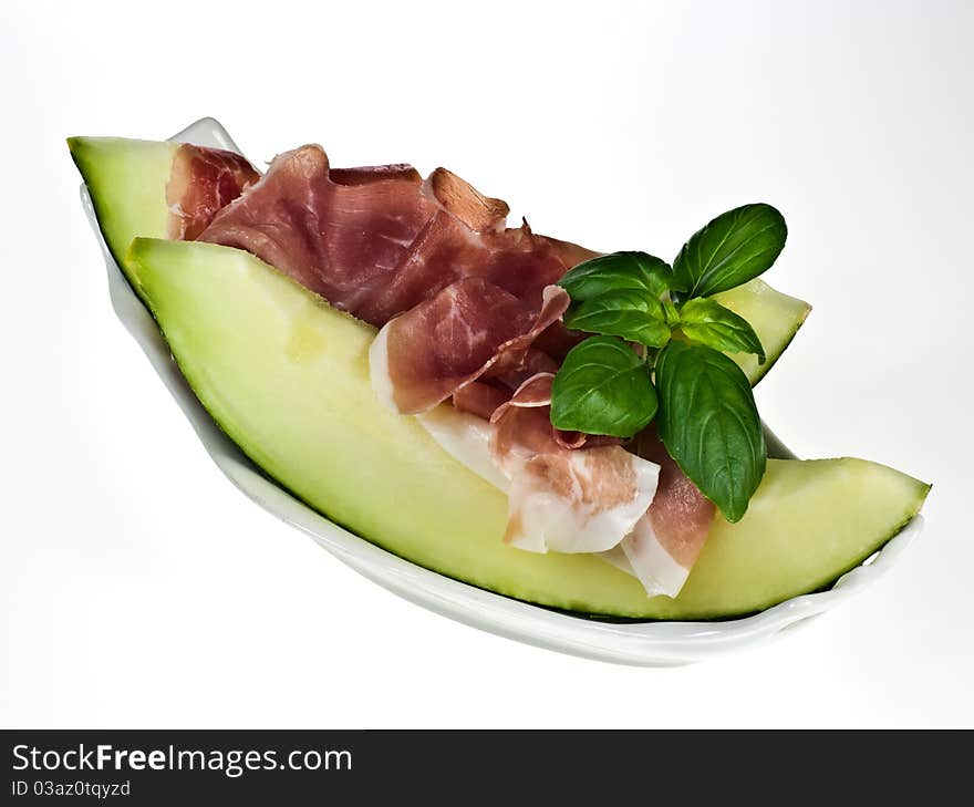 Melon with italian ham and basil leaves on porcelain dish. Melon with italian ham and basil leaves on porcelain dish