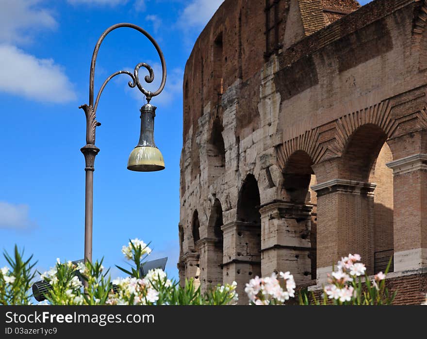 Ornate street lamp with Colosseum in background.