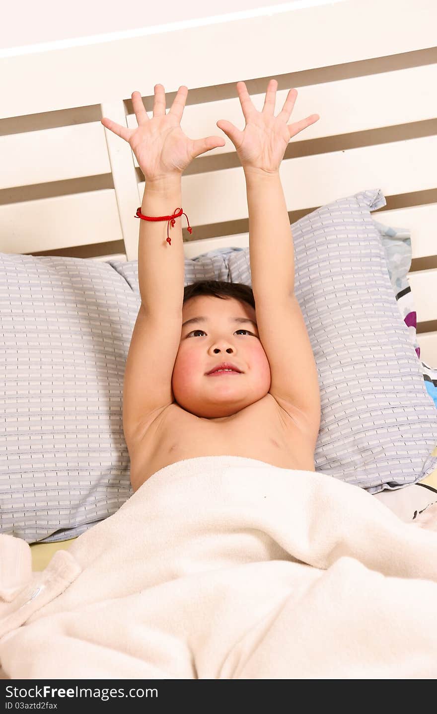 Picture of a little chinese boy yawning while lying on the bed. Picture of a little chinese boy yawning while lying on the bed