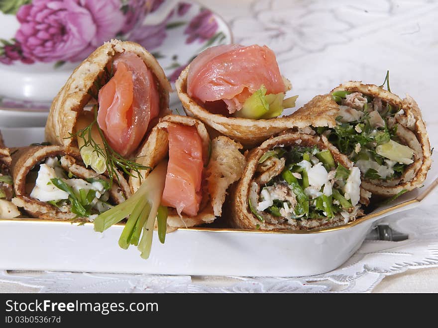 On a table there is a plate with pancakes and red fish. On a light background. On a table there is a plate with pancakes and red fish. On a light background