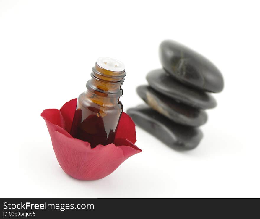 Rose petals, a bottle of aromatherapy oil and spa stones on white. Rose petals, a bottle of aromatherapy oil and spa stones on white