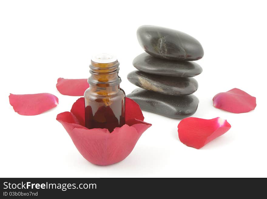 Rose petals, a bottle of aromatherapy oil and spa stones on white. Rose petals, a bottle of aromatherapy oil and spa stones on white