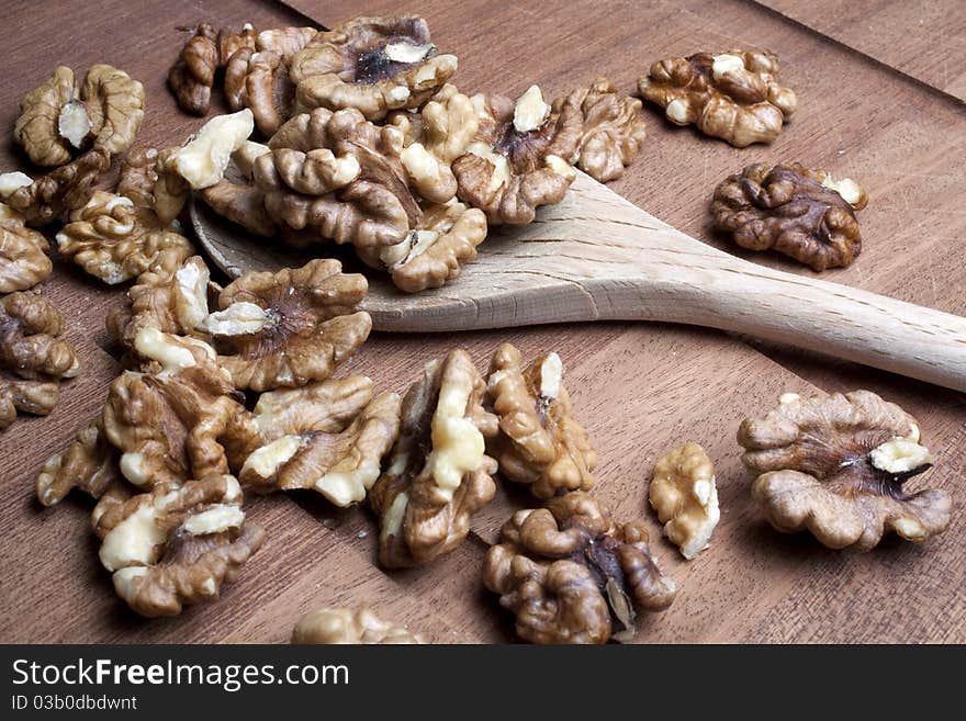 Walnuts on a wooden cutting board inside a kitchen on a wooden spoon