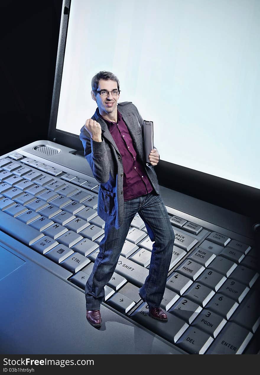 Conceptual photo of a happy man standing on the laptop's keyboard