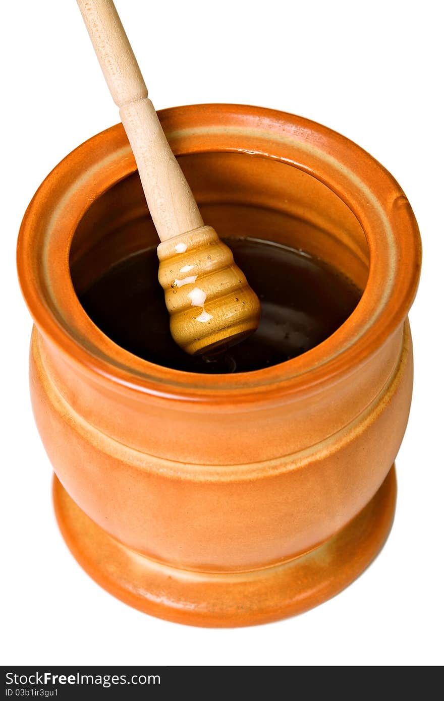 Ceramic jar with honey and wooden stick