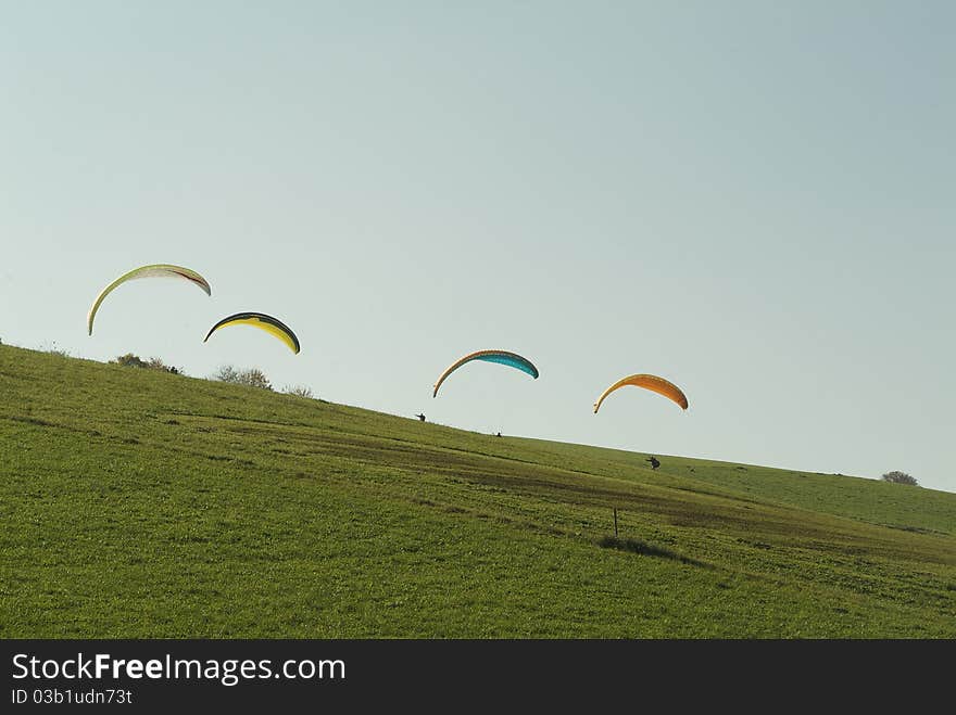 The paragliding people are using the thermal lift. The wind is ballooning the paragliders.