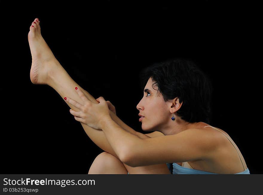 Portrait of young hispanic woman raising one leg, isolated on black. Portrait of young hispanic woman raising one leg, isolated on black