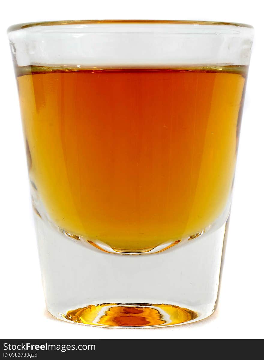 Beautiful side on shot of a shot glass full of brown whiskey or brandy. Beautiful side on shot of a shot glass full of brown whiskey or brandy