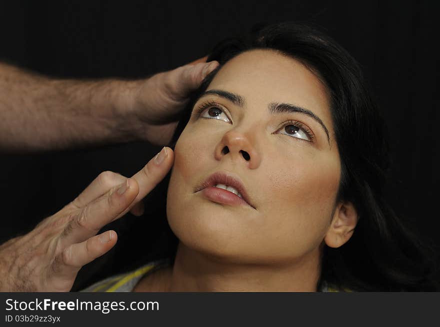 Hands applying make up on hispanic girl