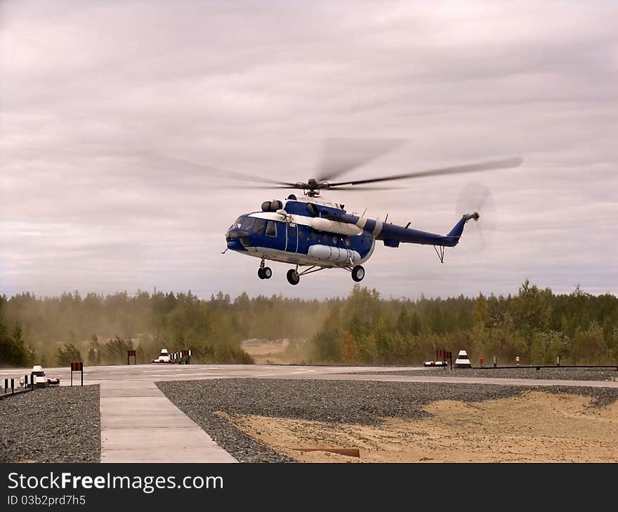 Helicopter fly over airport with green trees, summer