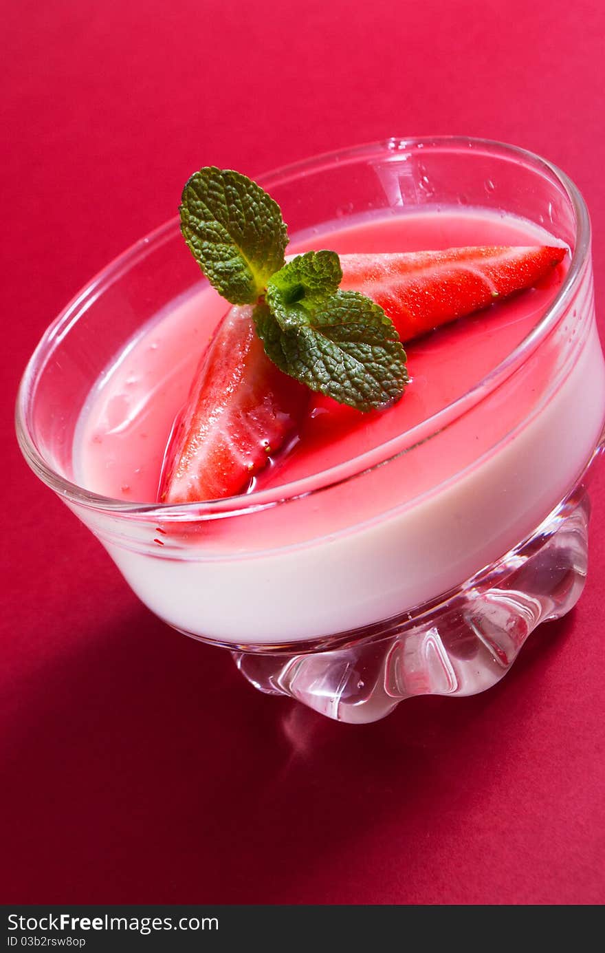 Italian dessert panna cotta on white plate decorated with strawbery, mint and fruit syrup. Italian dessert panna cotta on white plate decorated with strawbery, mint and fruit syrup