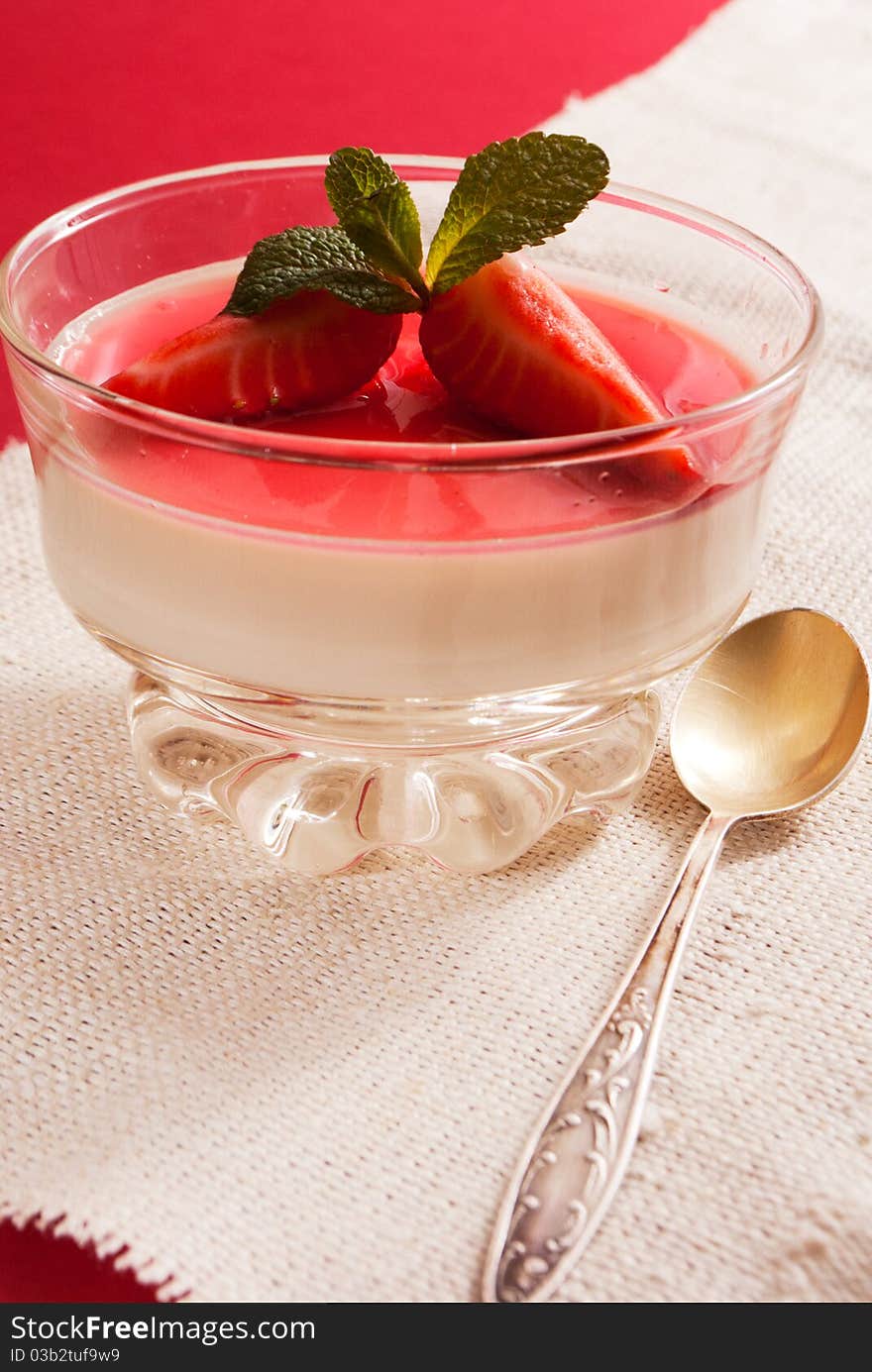 Italian dessert panna cotta on white plate decorated with strawbery, mint and fruit syrup. Italian dessert panna cotta on white plate decorated with strawbery, mint and fruit syrup