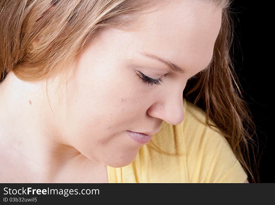 A woman looking down at something. She could be thinking, looking at a baby, or just concentrating on a piece of work.