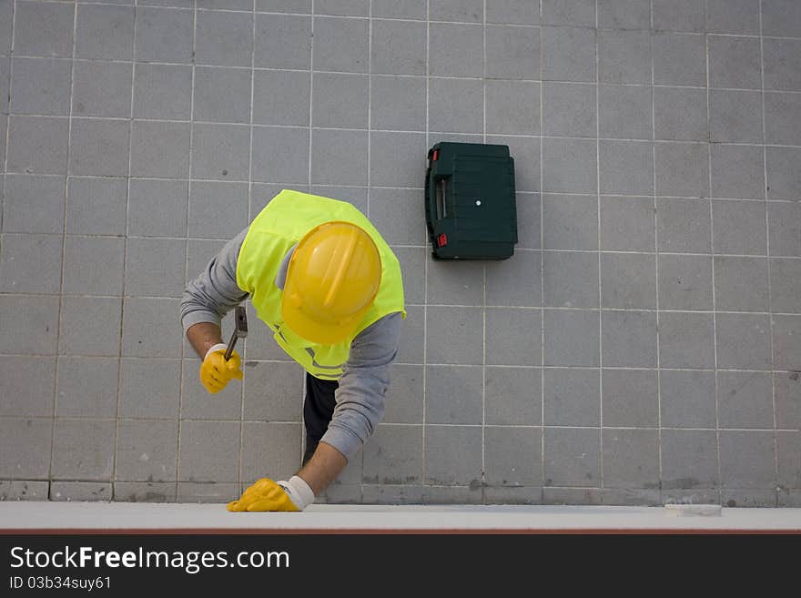 A worker hammering a nail into wall