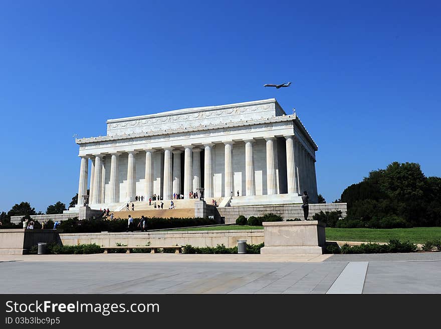 An airplane flying over the Lincoln Memorial in a clear, deep blue sky. An airplane flying over the Lincoln Memorial in a clear, deep blue sky.