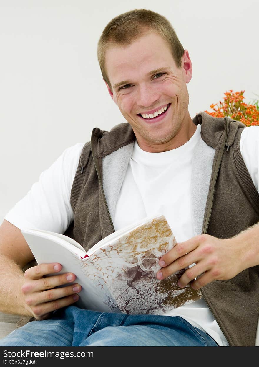 Young adult reading a book while he's lying on the couch. Young adult reading a book while he's lying on the couch