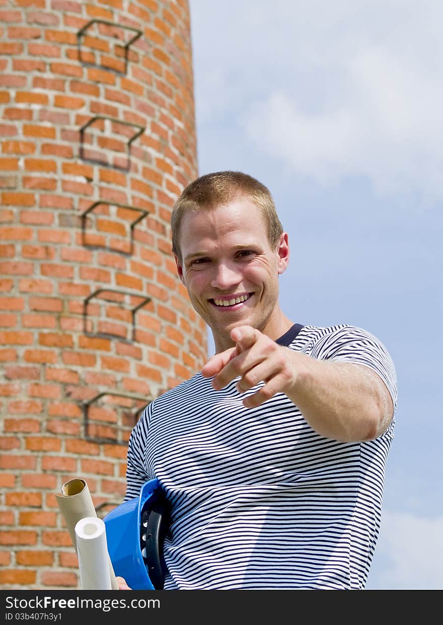 Successful man pointing to you in front of a brick building