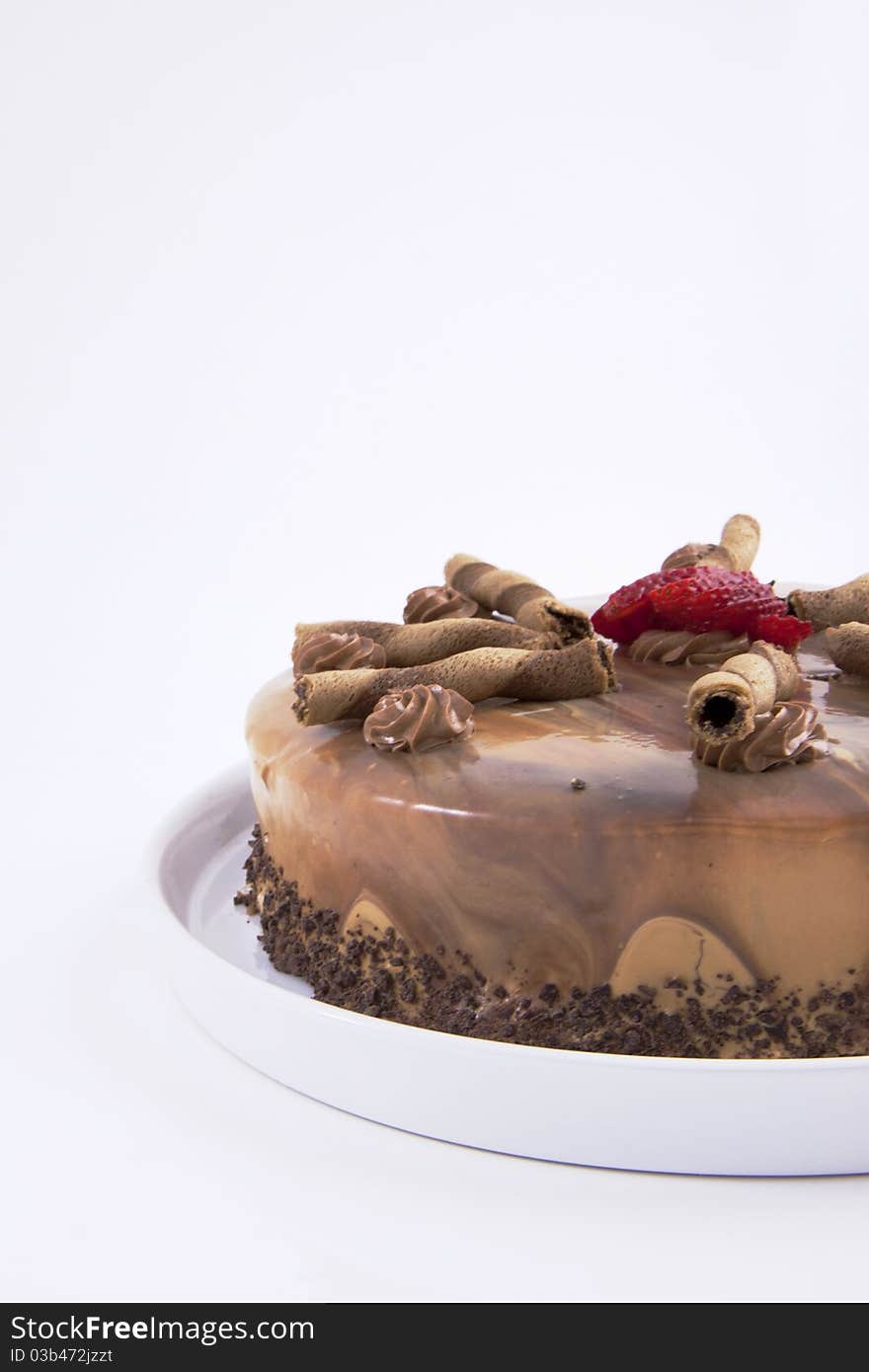 Partial view of a mocha cake with a strawberry on a plain white background