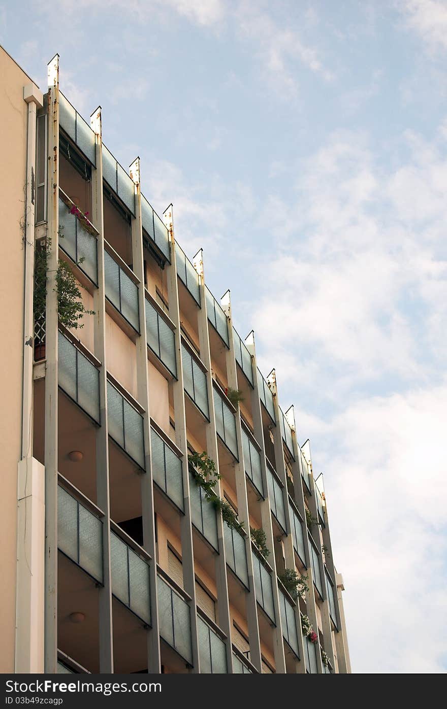 Top of new modern building with balcony and plants.