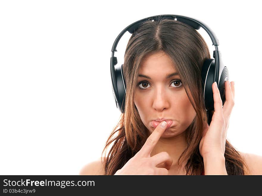 Attractive cheerful brunette woman listening and enjoying music in headphones, one hand finger touch mouth isolated on a white background. Attractive cheerful brunette woman listening and enjoying music in headphones, one hand finger touch mouth isolated on a white background