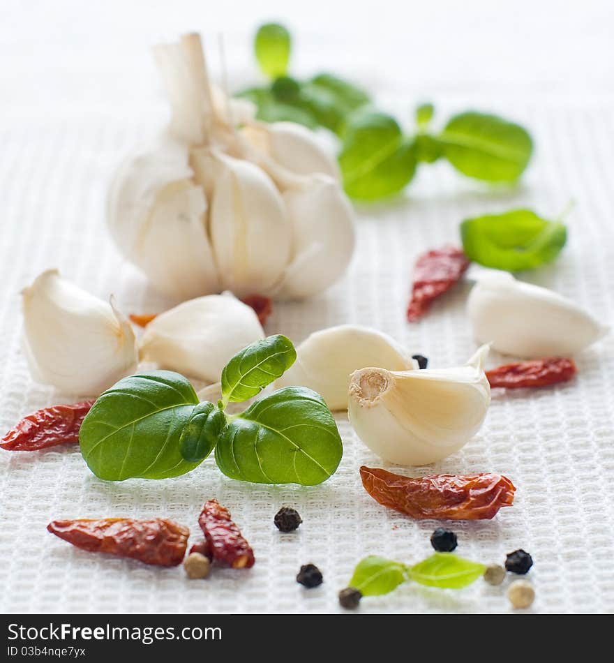 Garlic, dried chili pepper, black pepper and basil on kitchen towel. Garlic, dried chili pepper, black pepper and basil on kitchen towel