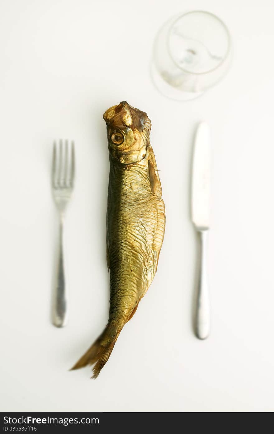 dried aringa fish isolated on white with fork knife and glass