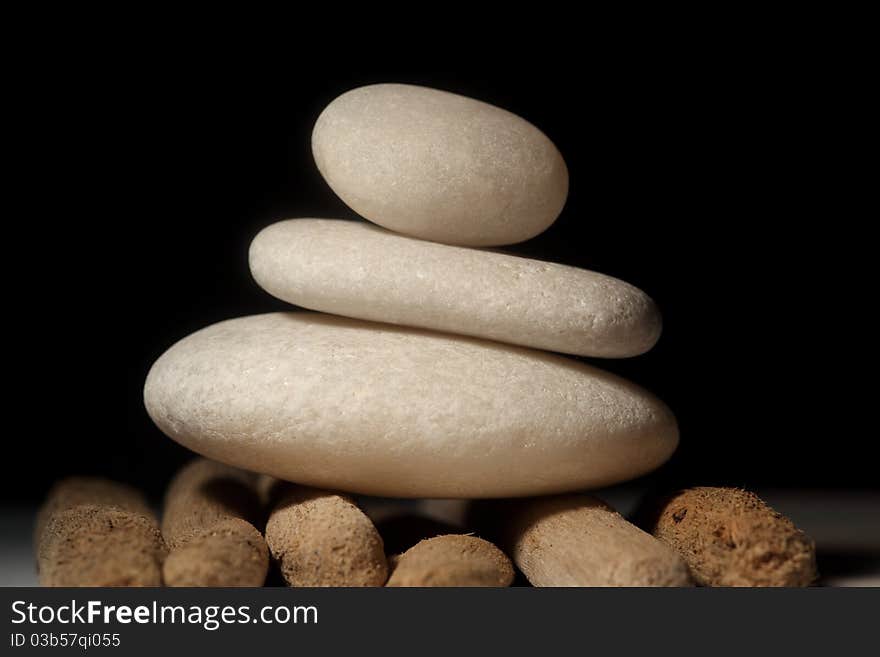 Three stones balancing on each other on drift wood and black backdrop. Three stones balancing on each other on drift wood and black backdrop