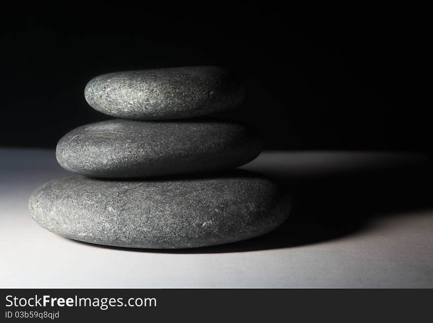 Three stones balancing on each other and black backdrop. Three stones balancing on each other and black backdrop