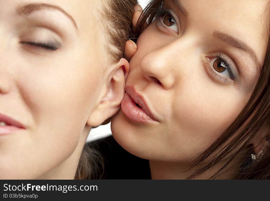 Two young girlfriends sharing their secrets, studio shot