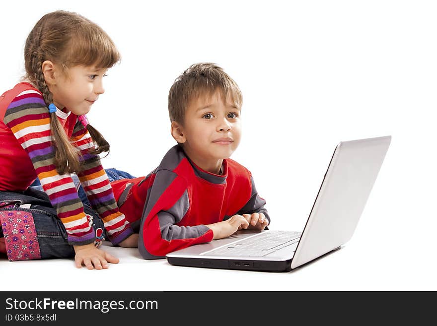 Two kids looking at notebook - laying flat on the floor. Two kids looking at notebook - laying flat on the floor