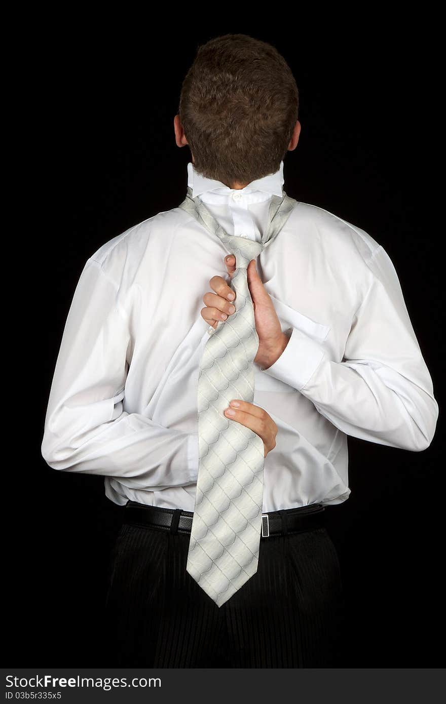 Businessman back, tying tie, concept help assistance, isolated on black, low key. Businessman back, tying tie, concept help assistance, isolated on black, low key.