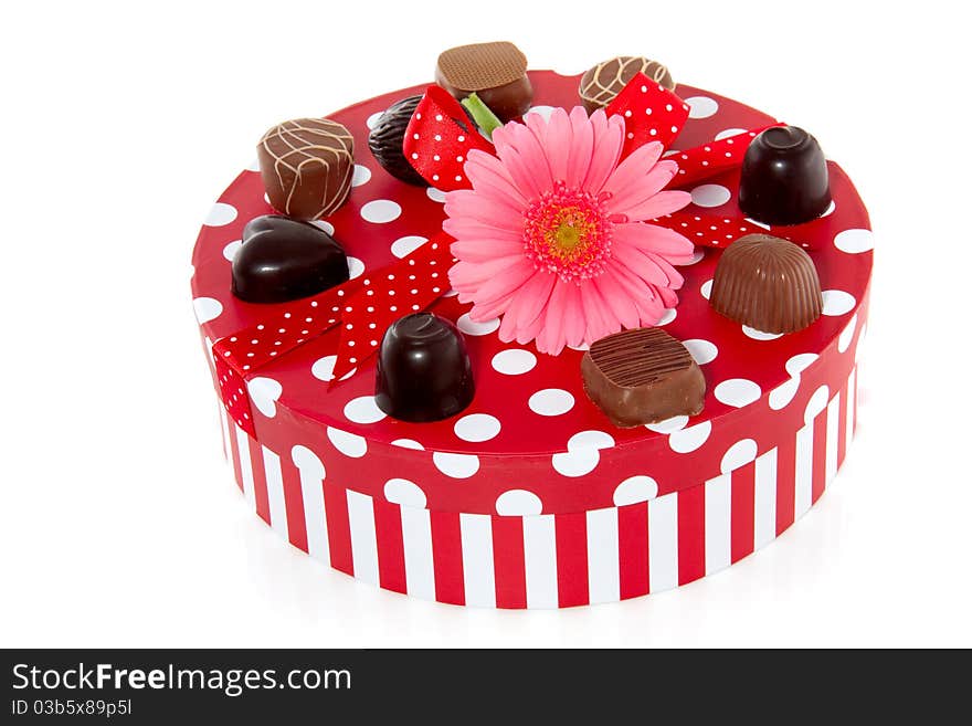 A red dotted gift-box with a pink gerbera on top isolated over white background. A red dotted gift-box with a pink gerbera on top isolated over white background