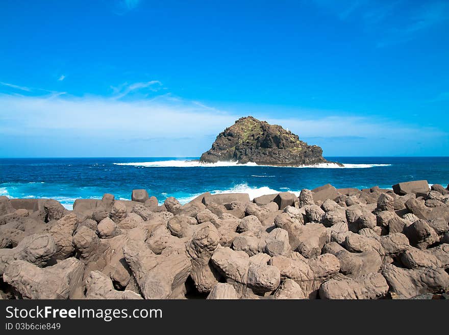 A view of an island in tenerife with rocks in the foreground. A view of an island in tenerife with rocks in the foreground