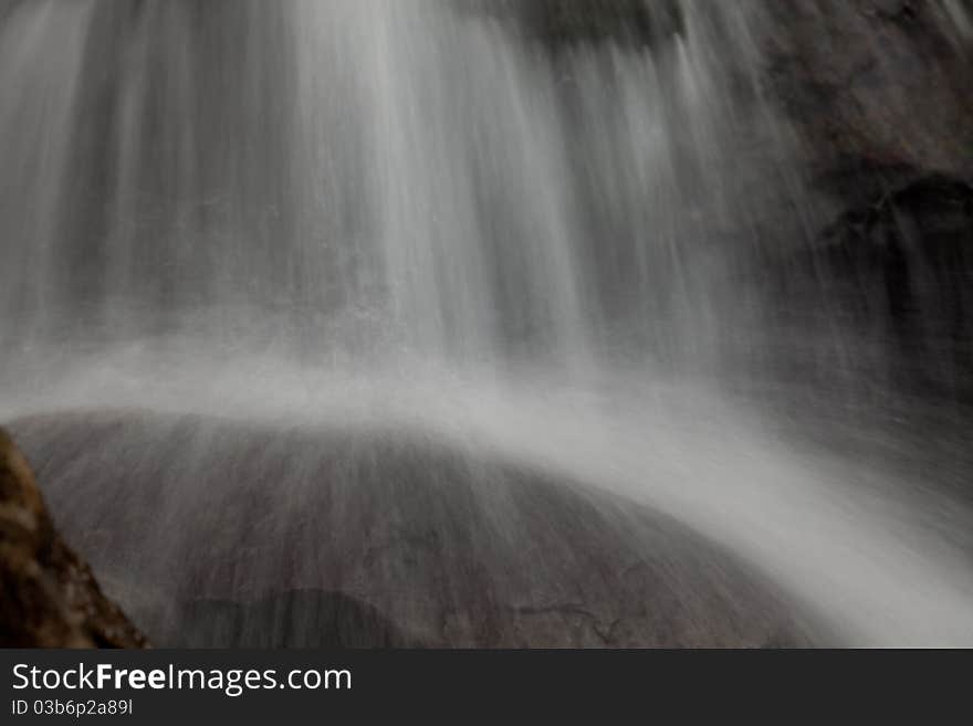 Cascade falls over old plum river with rocks