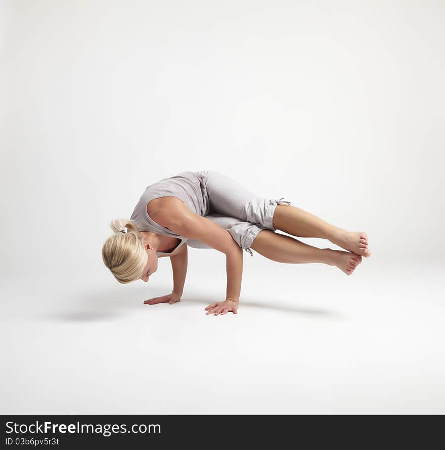 Young woman doing yoga exercise on white background