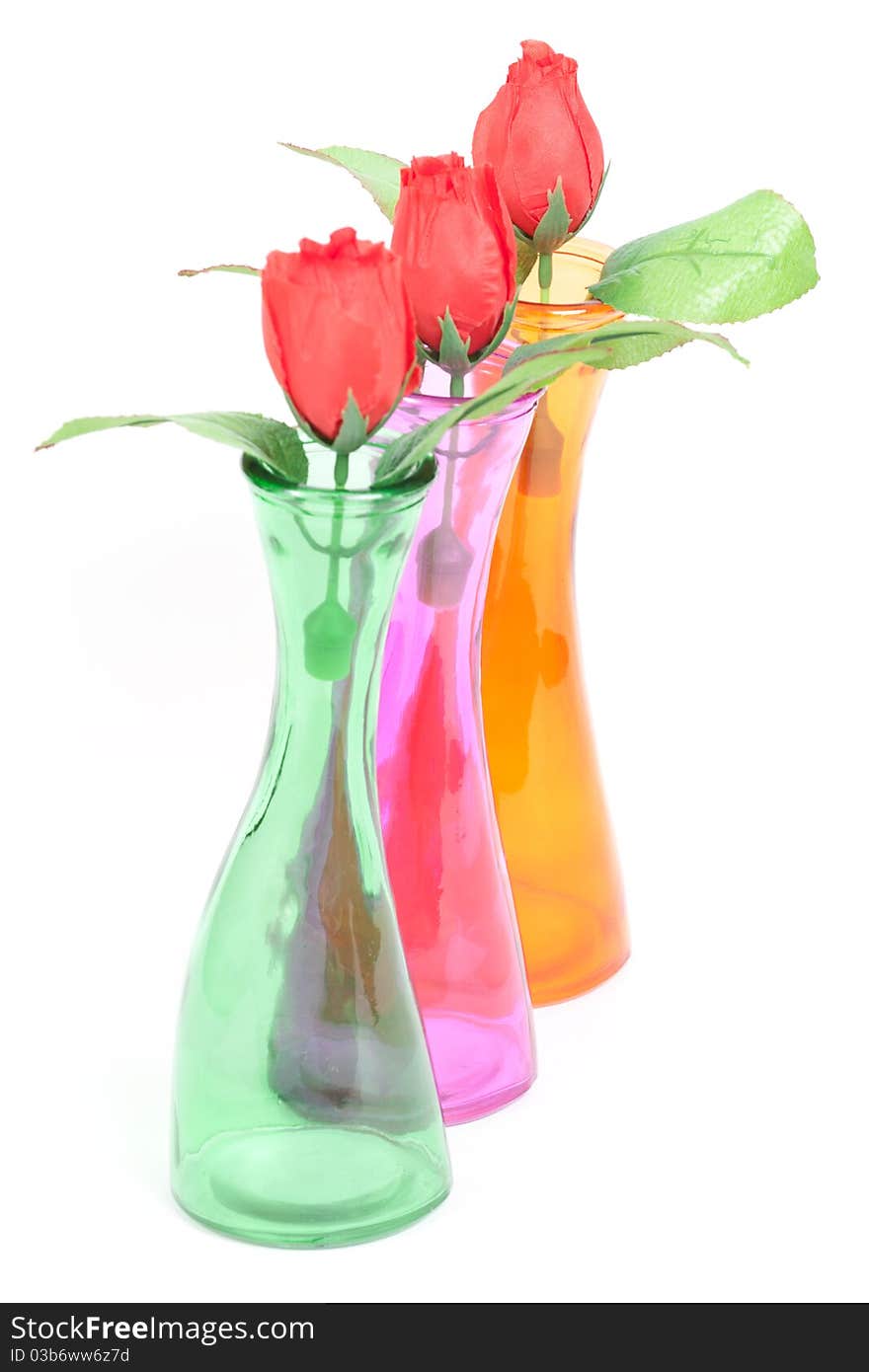 Glass color vases with roses isolated on white background