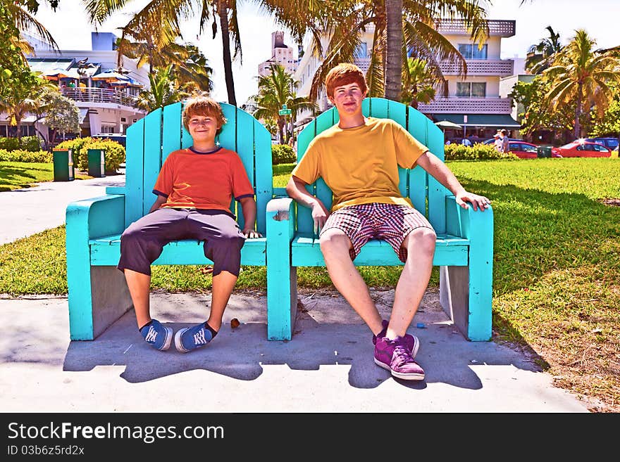 Two brothers are sitting on a art deco park bench in south Miami, the Art deco district