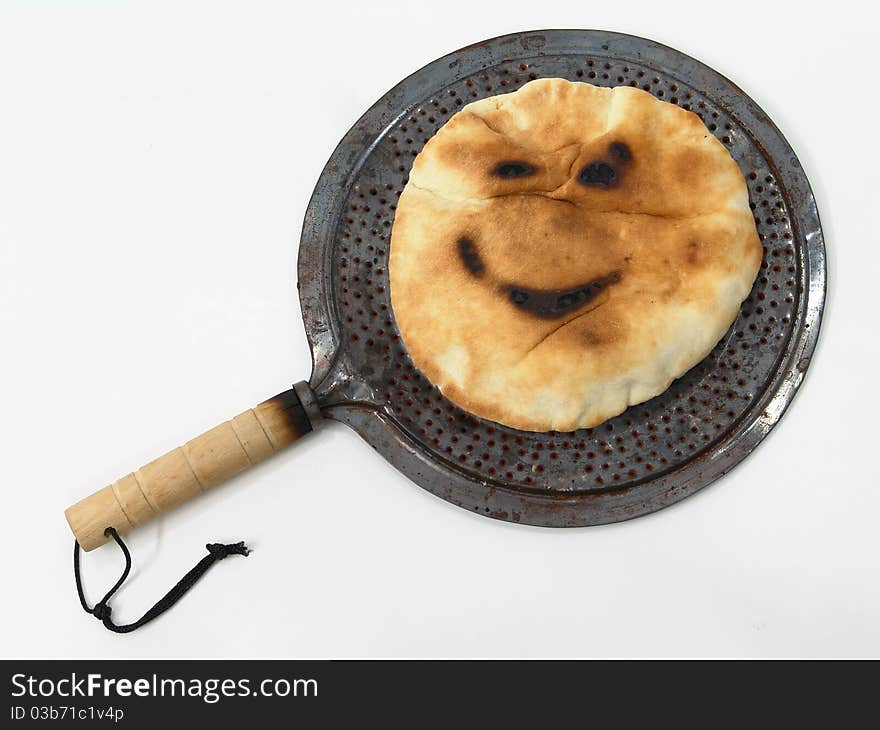 A shot of a rounded bread that is burnt in some parts of it that made it look like a smiley face. A shot of a rounded bread that is burnt in some parts of it that made it look like a smiley face