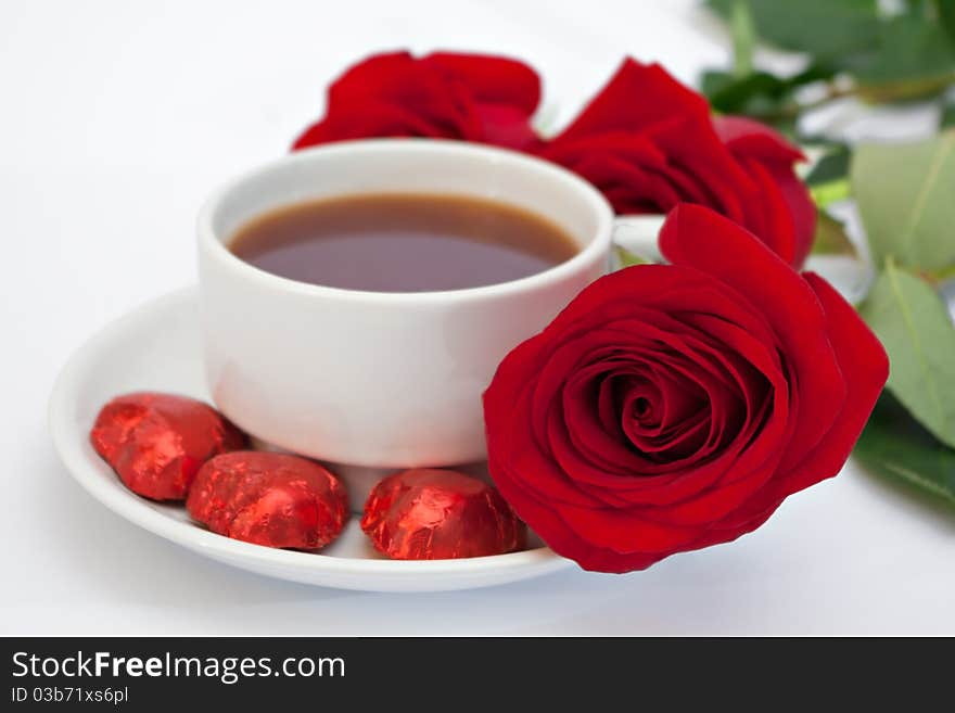 Red roses next to cups of tea. Red roses next to cups of tea