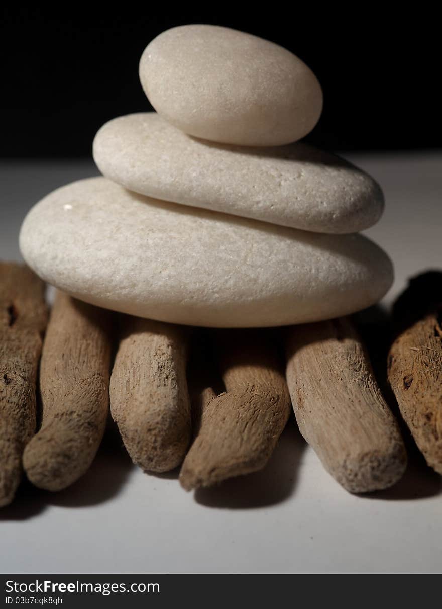 Three stones balancing on each other on drift wood and black backdrop. Three stones balancing on each other on drift wood and black backdrop