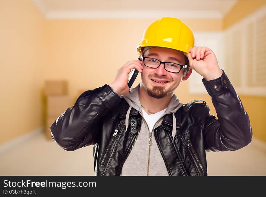 Young Contractor Wearing Hard Hat on Cell Phone Inside Empty House. Young Contractor Wearing Hard Hat on Cell Phone Inside Empty House.