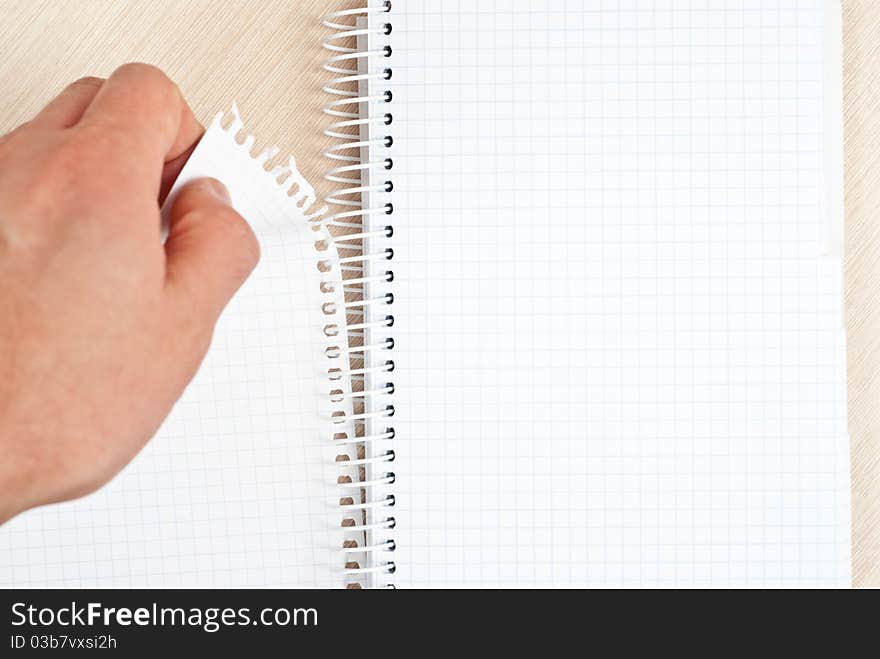 Hand tearing one paper page from notepad on desk. Hand tearing one paper page from notepad on desk