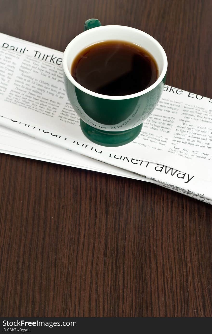 Hot cup of coffee and newspaper on dark desk. Hot cup of coffee and newspaper on dark desk