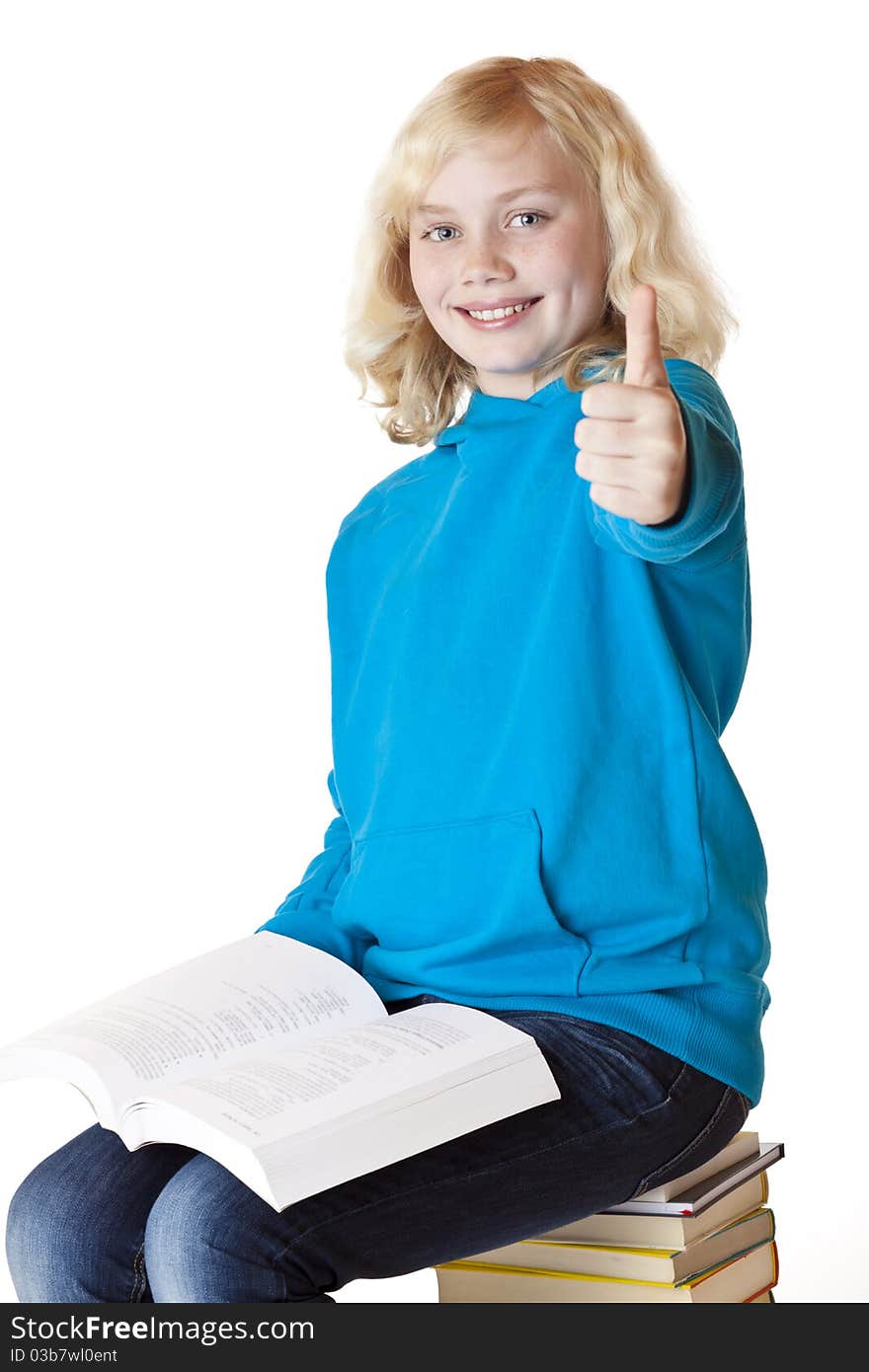 Happy schoolgirl sitting on books showing thumb