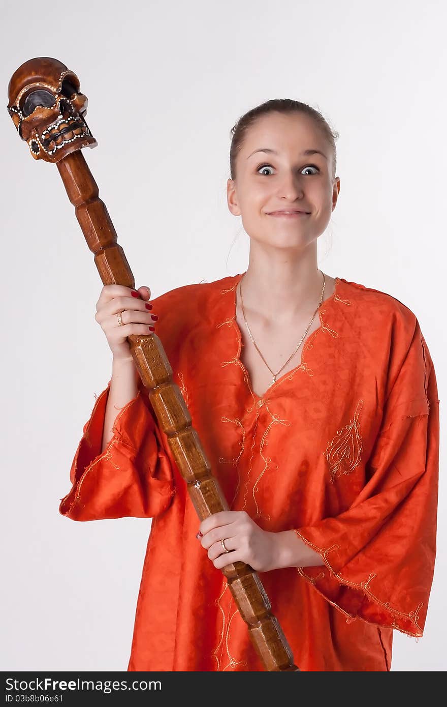 Girl in orange dress on a light background with a staff. Girl in orange dress on a light background with a staff