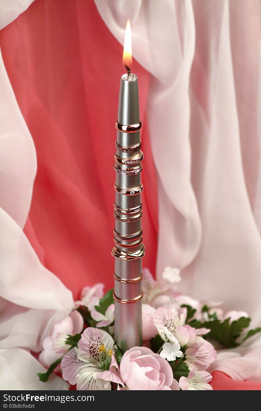 Gold rings adorn the metal rod with a candle. Gold rings adorn the metal rod with a candle