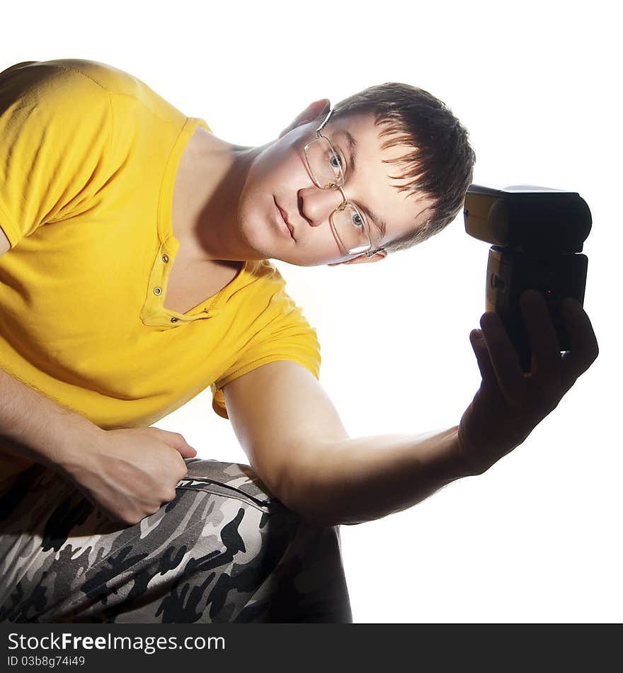 Guy with glasses and yellow shirt. Illuminates himself flash in his left hand. Isolated on a white background. Guy with glasses and yellow shirt. Illuminates himself flash in his left hand. Isolated on a white background.