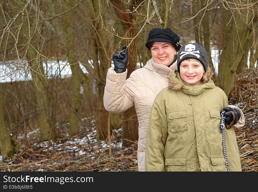 Happy mother and son walking in the winter forest