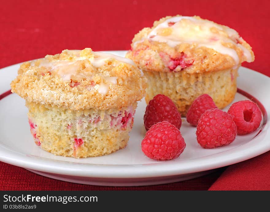 Two raspberry muffins with raspberry fruit on a plate