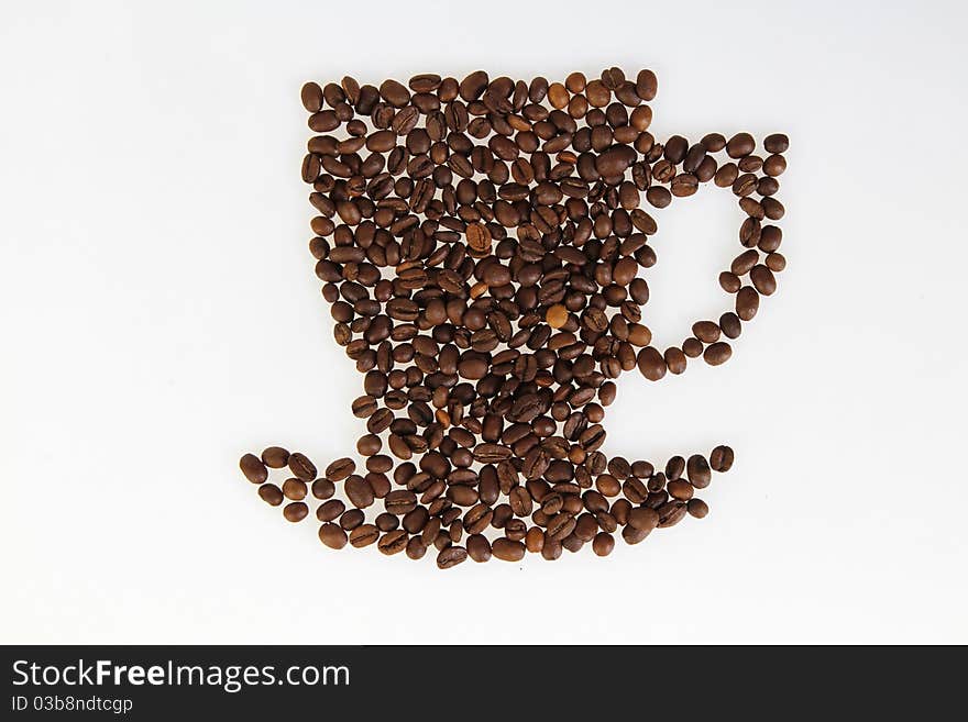 Roasted beans gathered in a shape of coffee cup on the white background